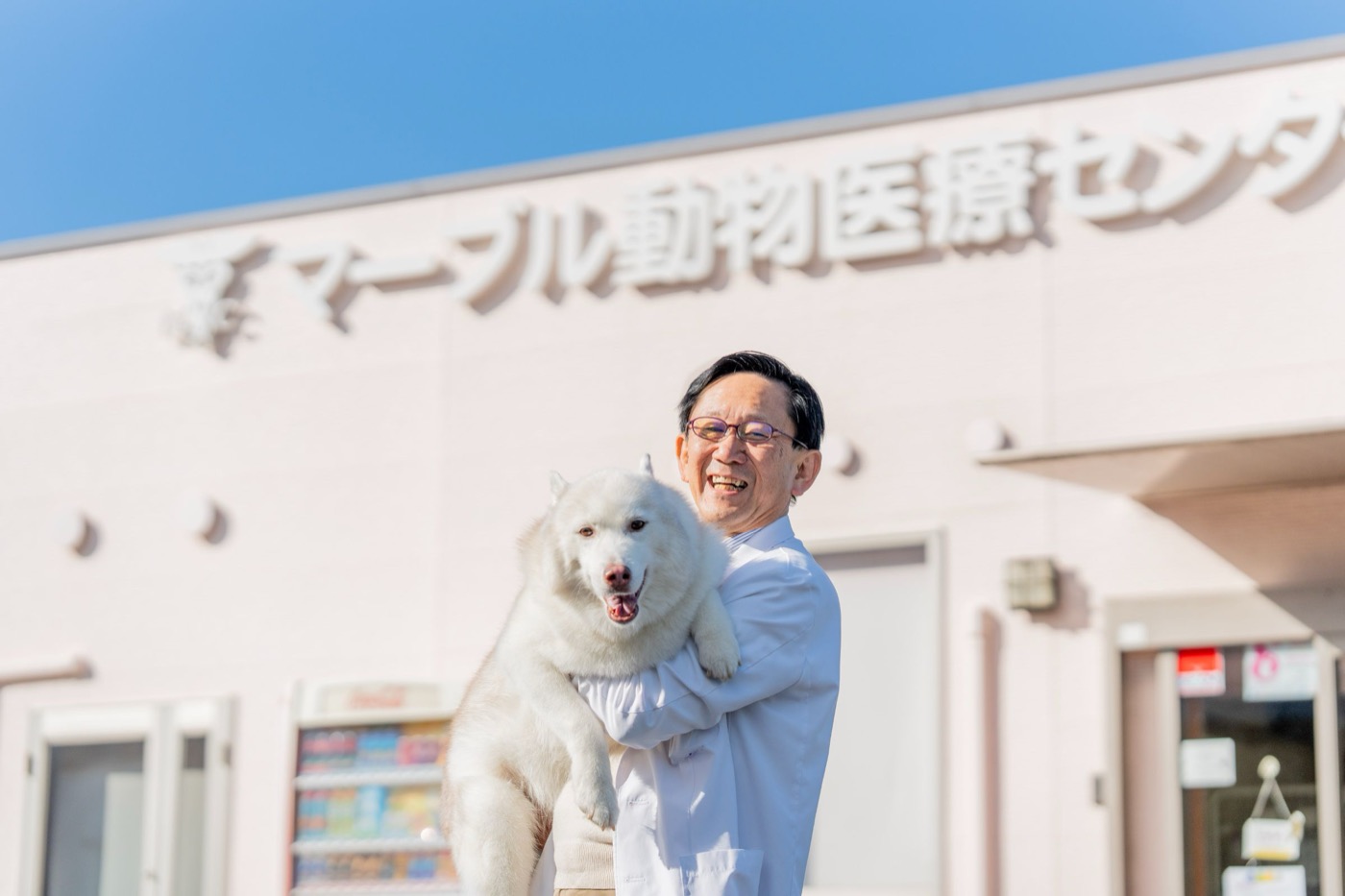 病院の前で犬を抱く院長